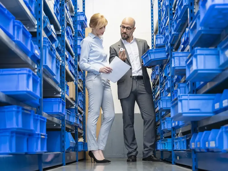 Businessman And Businesswoman Examining Workpiece